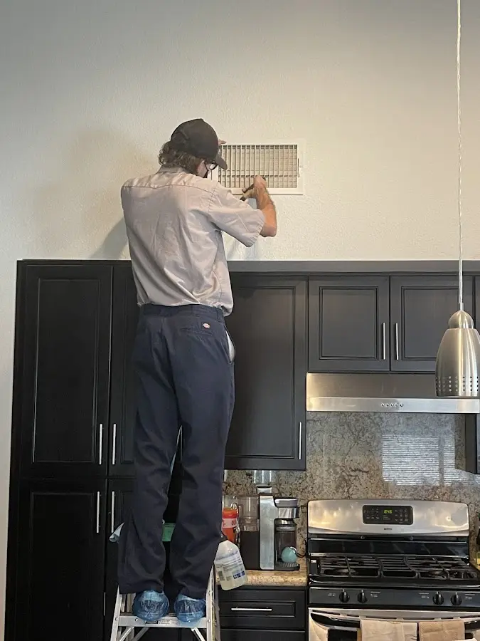 Technician inspecting an air vent during HVAC service in Ashtabula